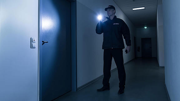 Sicherheitsmann mit Taschenlampe vor der Tür